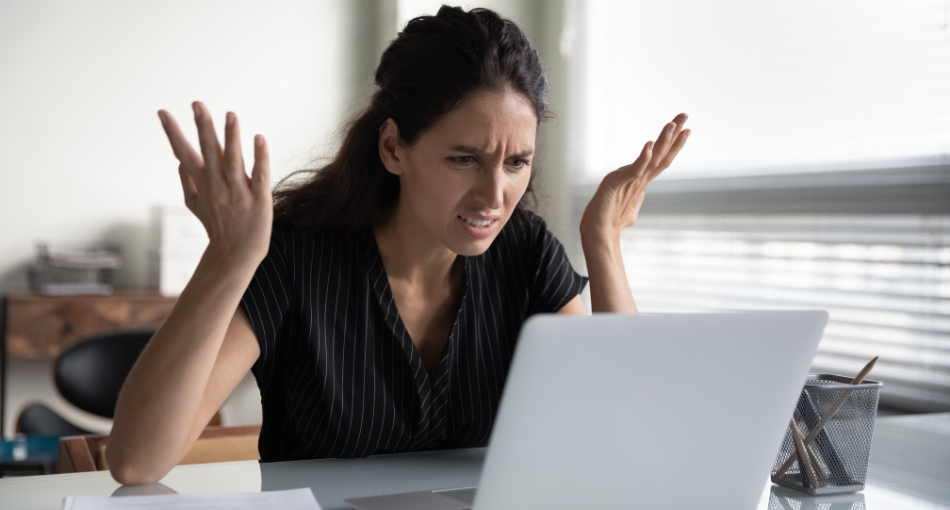 A woman sits frustrated at a computer.