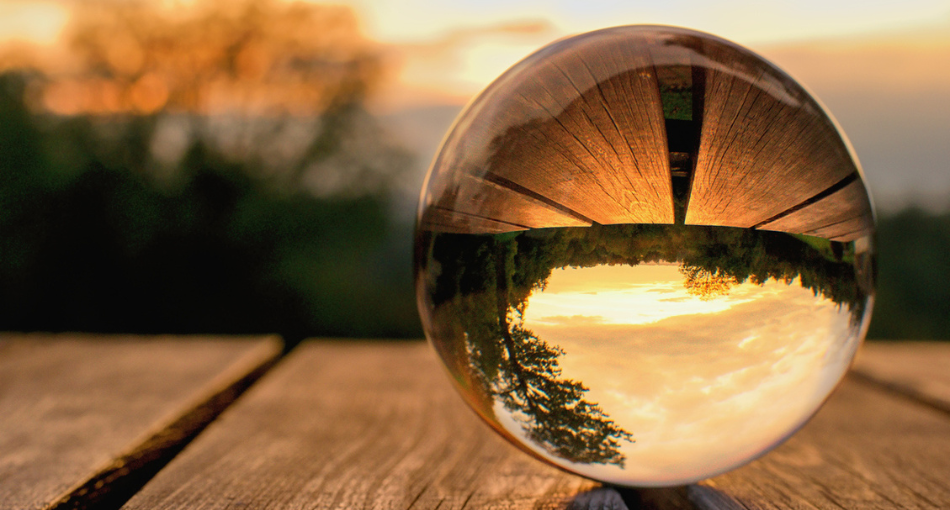 Lens ball on a table inverting a landscape in the background. Learn more about how predictions can't simply tell the future, but can be useful for revenue teams planning what to do next.